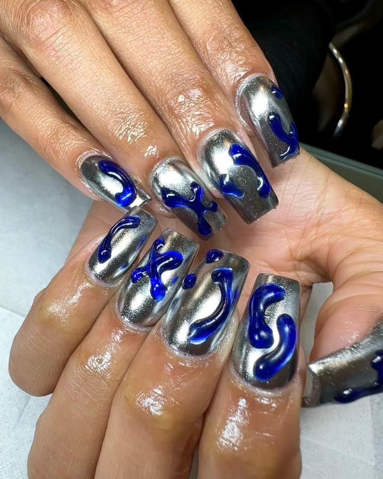 Long coffin nails with a silver chrome finish and raised cobalt-blue swirl designs