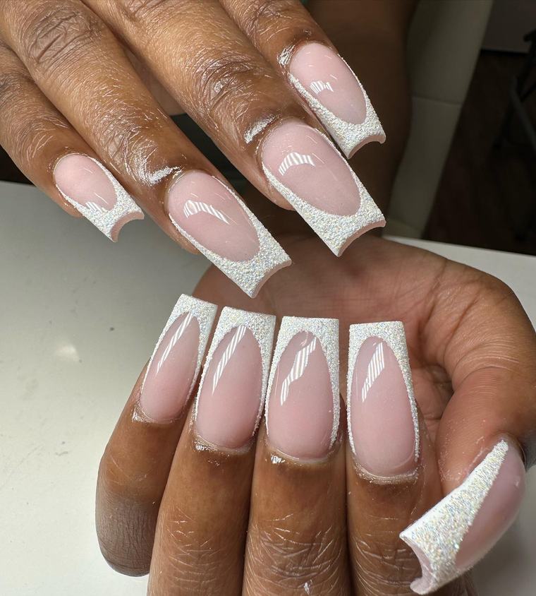 Long square nails with a soft pink base and glittery silver French tips