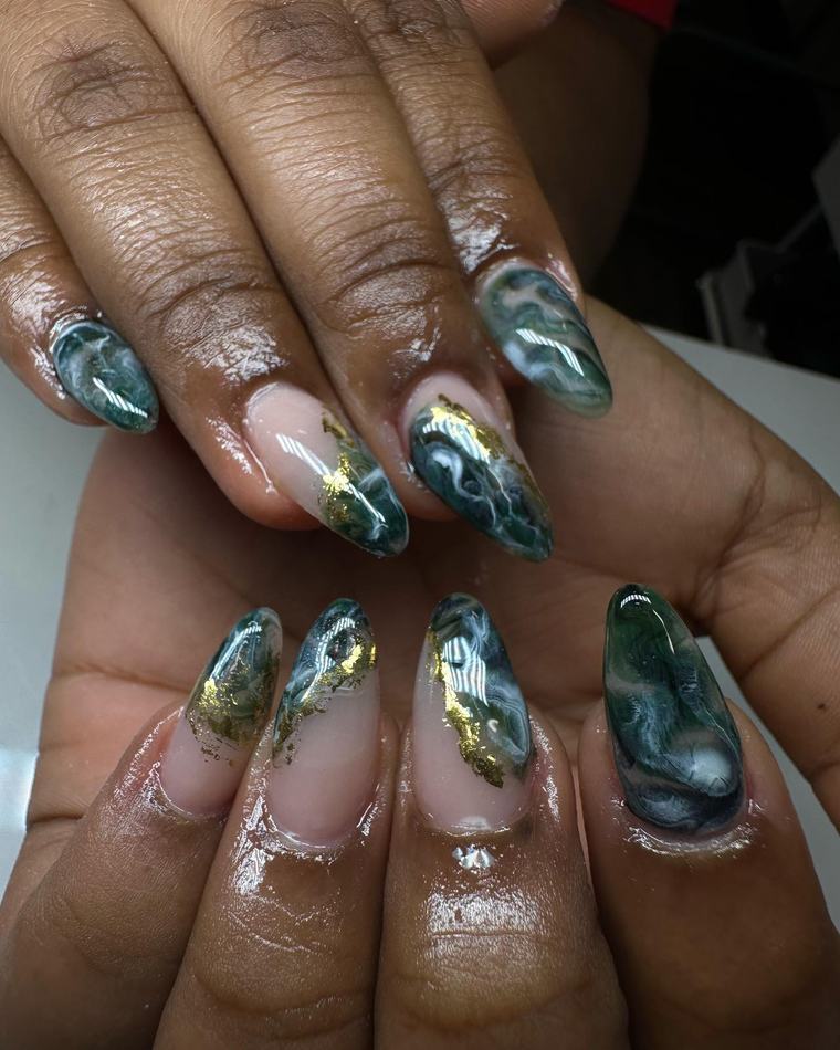 Almond-shaped nails with a green marble effect and gold foil accents