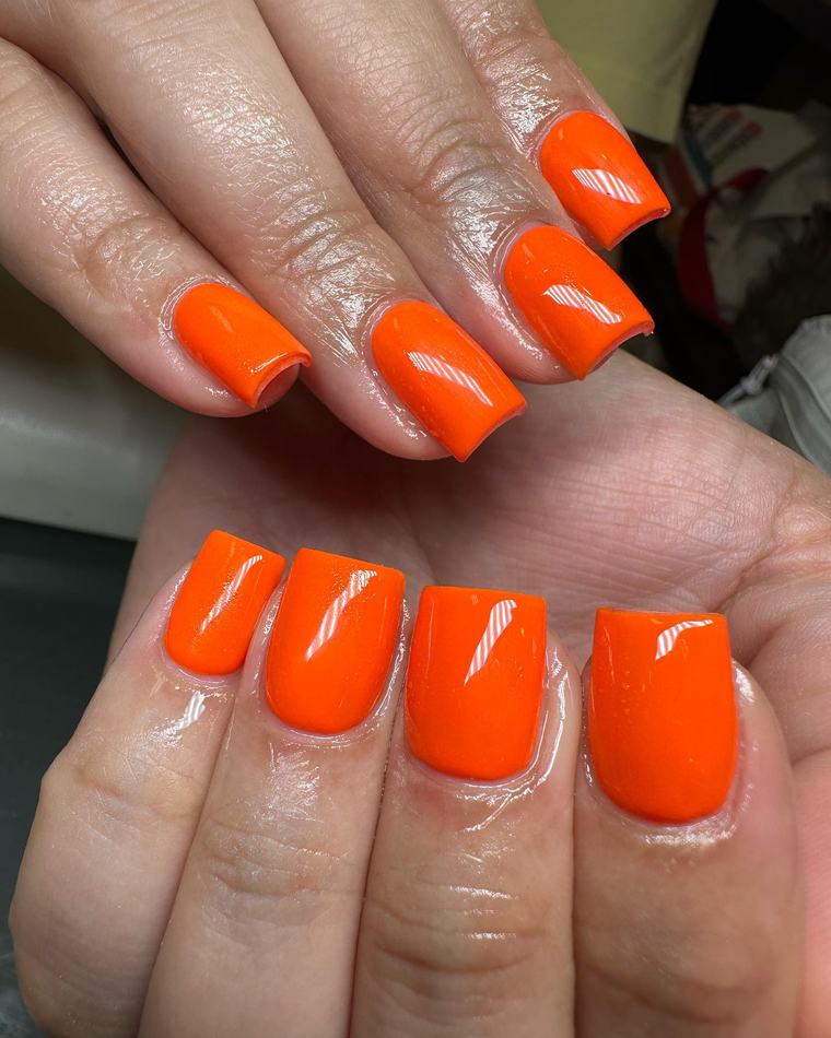 Short square nails in a glossy bright orange polish